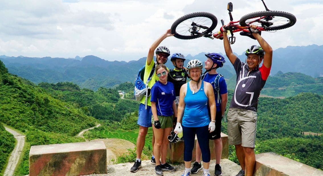 Los ciclistas se toman una foto grupal sosteniendo una divertida bicicleta de montaña en el tour ciclista de la ciudad de Nuwara Eliya