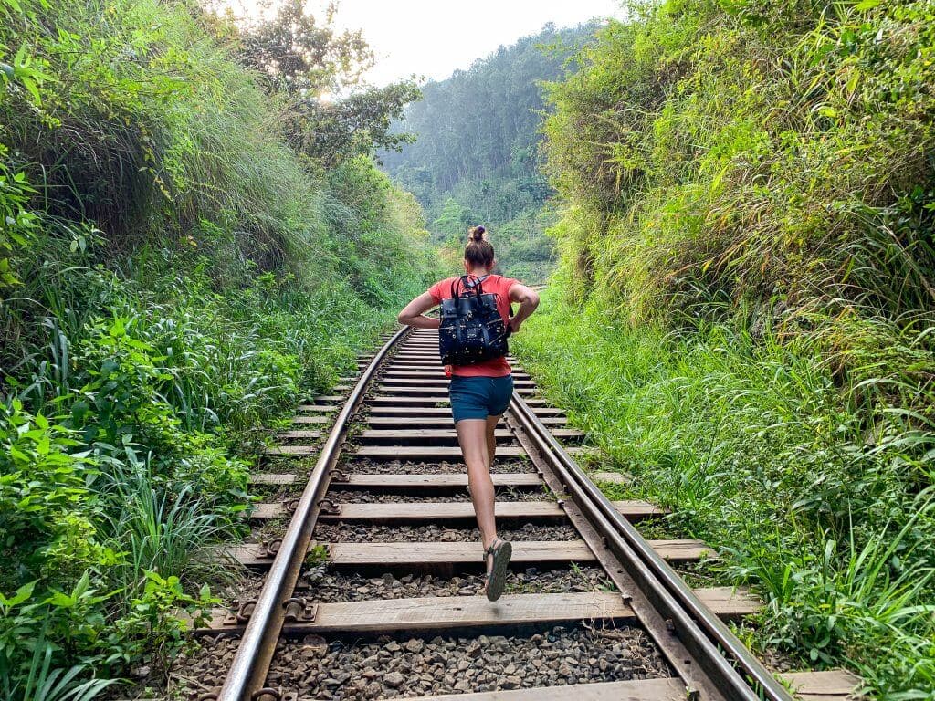 Молодая девушка идет по железной дороге Хилоя через флору и фауну Шри-Ланки.
