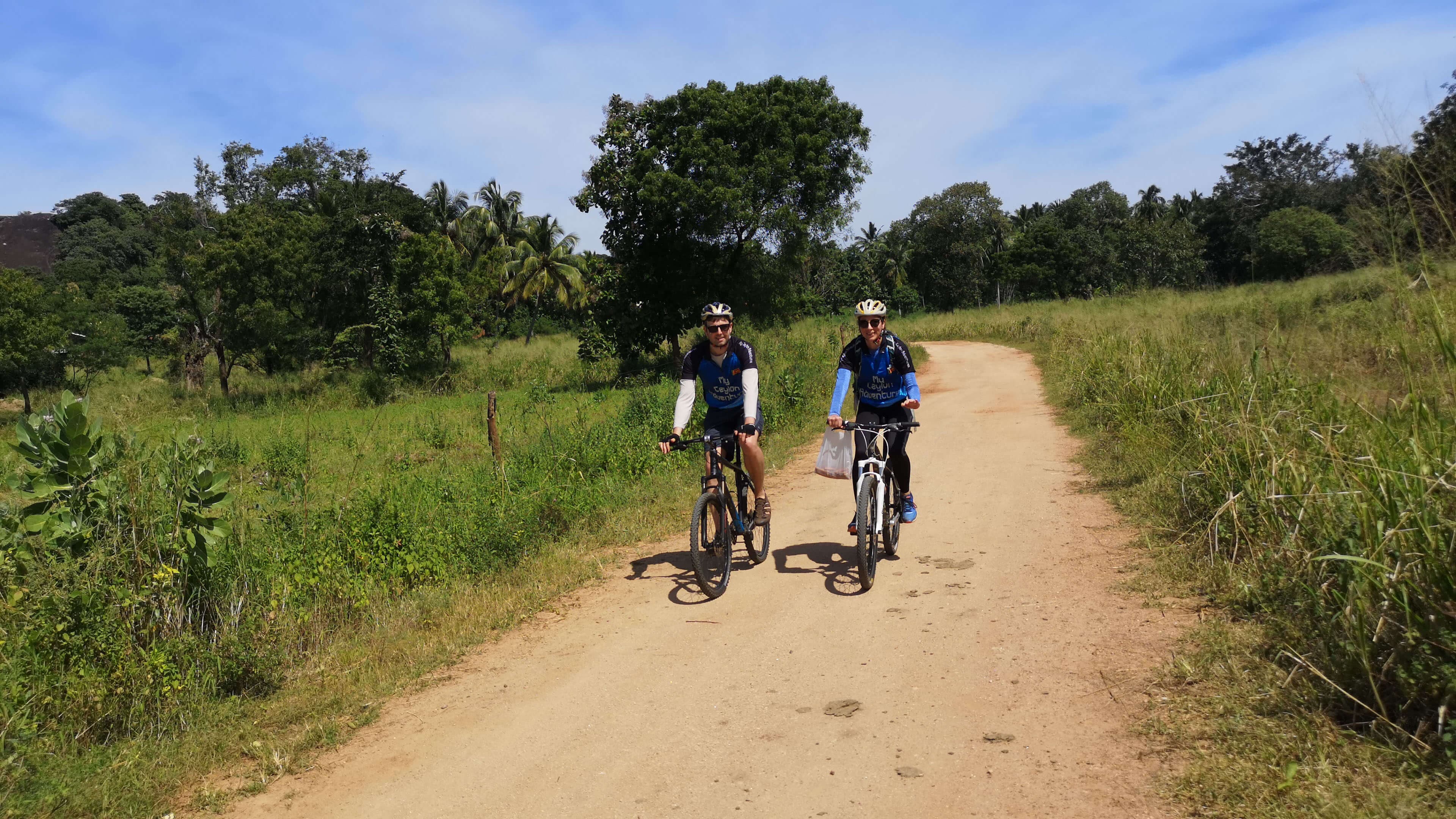 Два велосипедиста едут на велосипеде по засушливой зоне Удавалаве в Шри-Ланке.