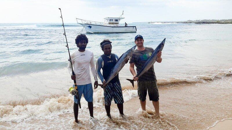 Турист поймал рыбу и пришел на пляж после рыбалки в Хиккадуве, Шри-Ланка.