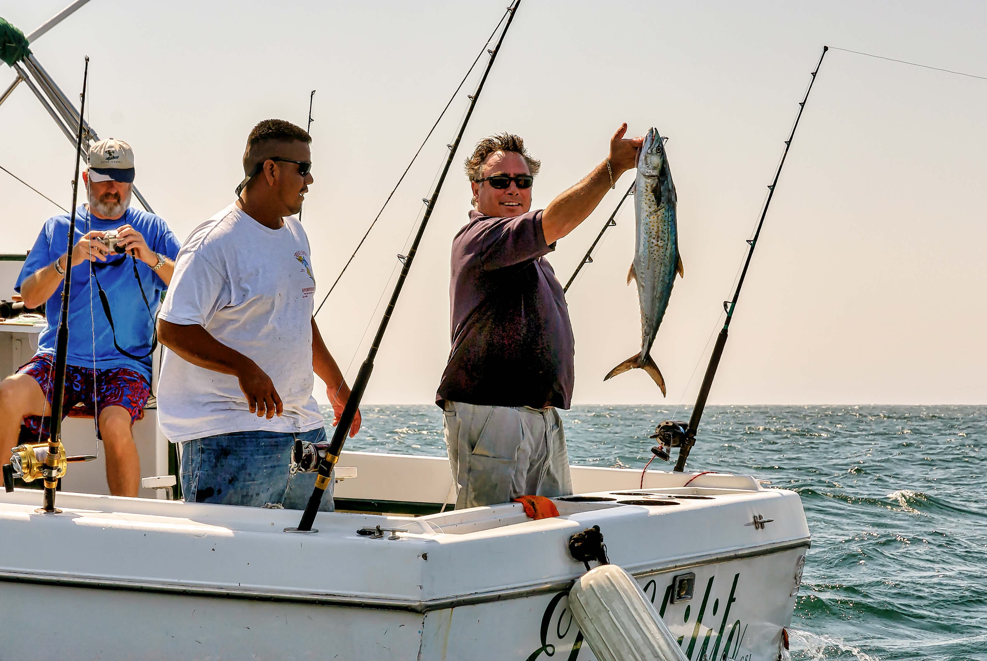 Трое туристов ловят рыбу, а один мужчина ловит рыбу во время рыболовного тура в Мириссе, Шри-Ланка.