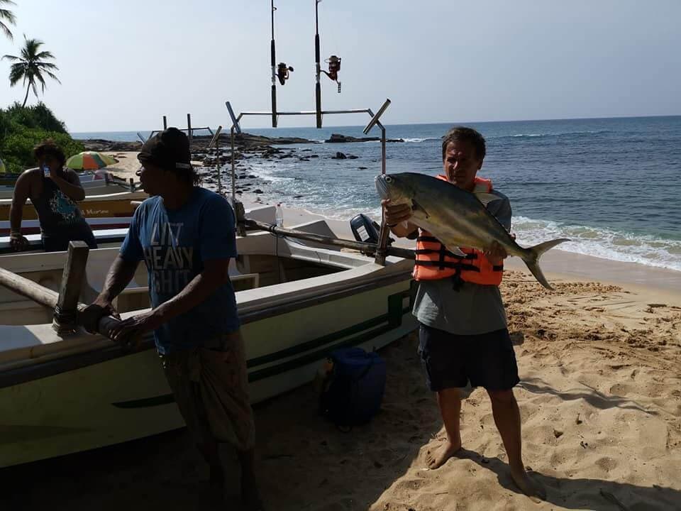 El turista trae el pez Trevally a la playa después del tour de pesca Tangalle Sri Lanka