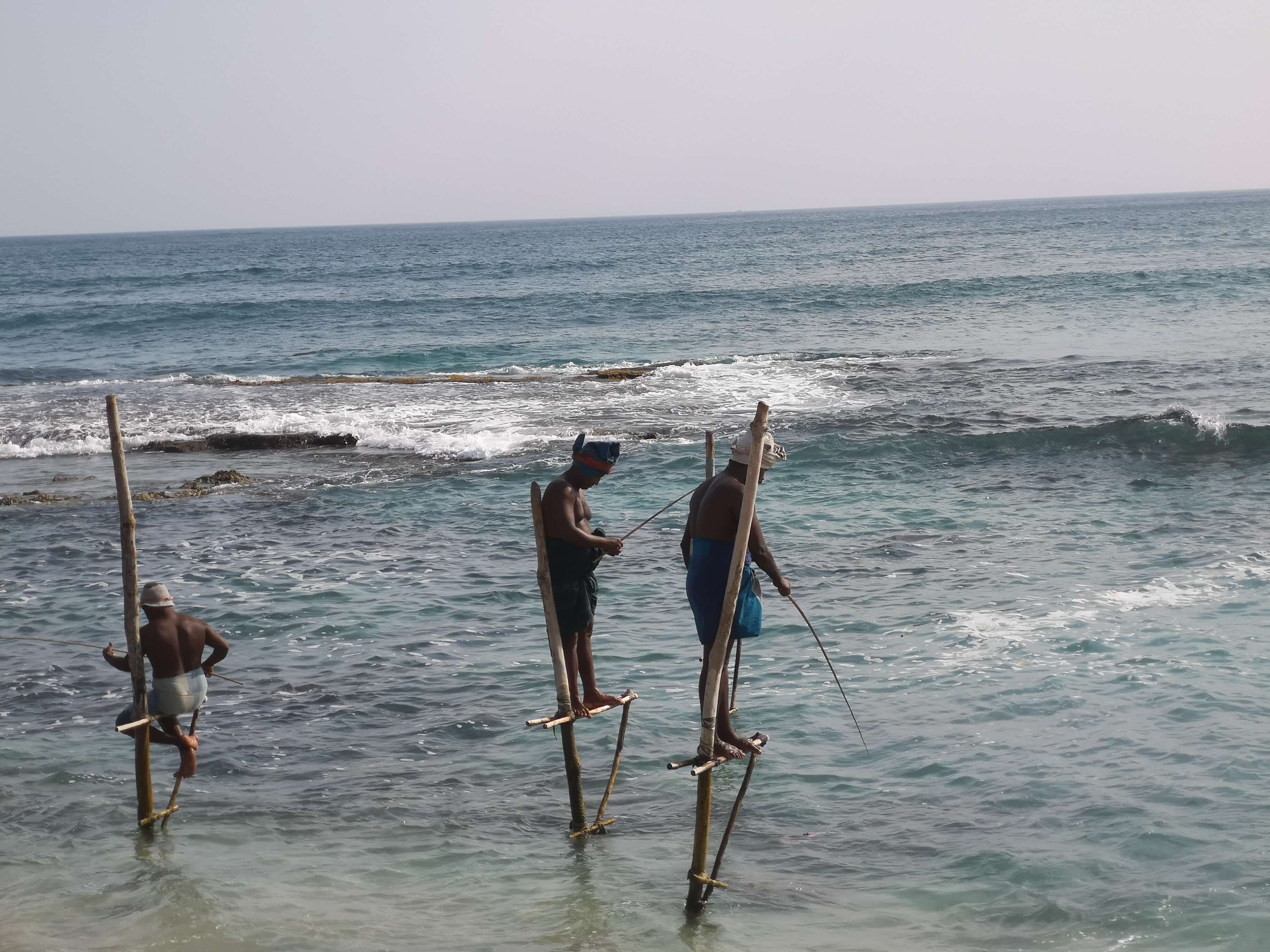 Una vista de tres pescadores pescando con la forma de pesca tradicional llamada 'pesca con zancos'