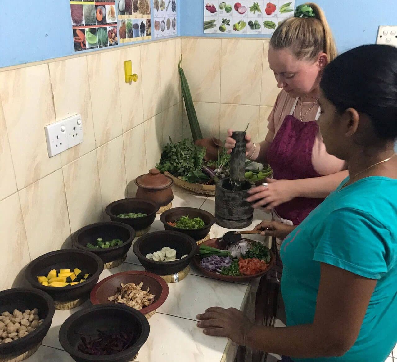 Туристка получает кулинарный опыт под руководством шри-ланкийской женщины в Шри-Ланке.
