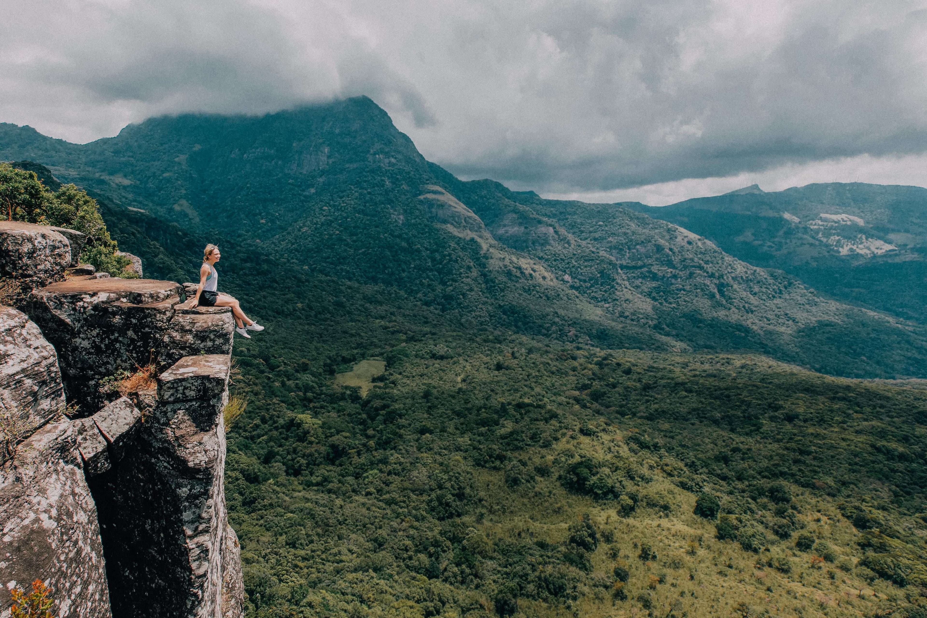 Ein Mädchen sitzt auf einem Gipfel des Berges und sieht schöne Szenen in der Gegend von Knuckles in Sri Lanka aus