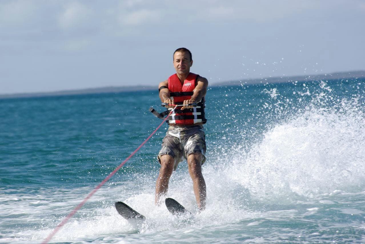 Мужчина катается на водных лыжах, брызгая водой
