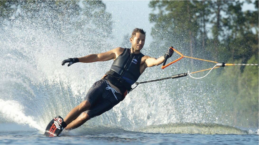 Мужчина катается на водных лыжах одной рукой и плещется в реке Бентота в Шри-Ланке