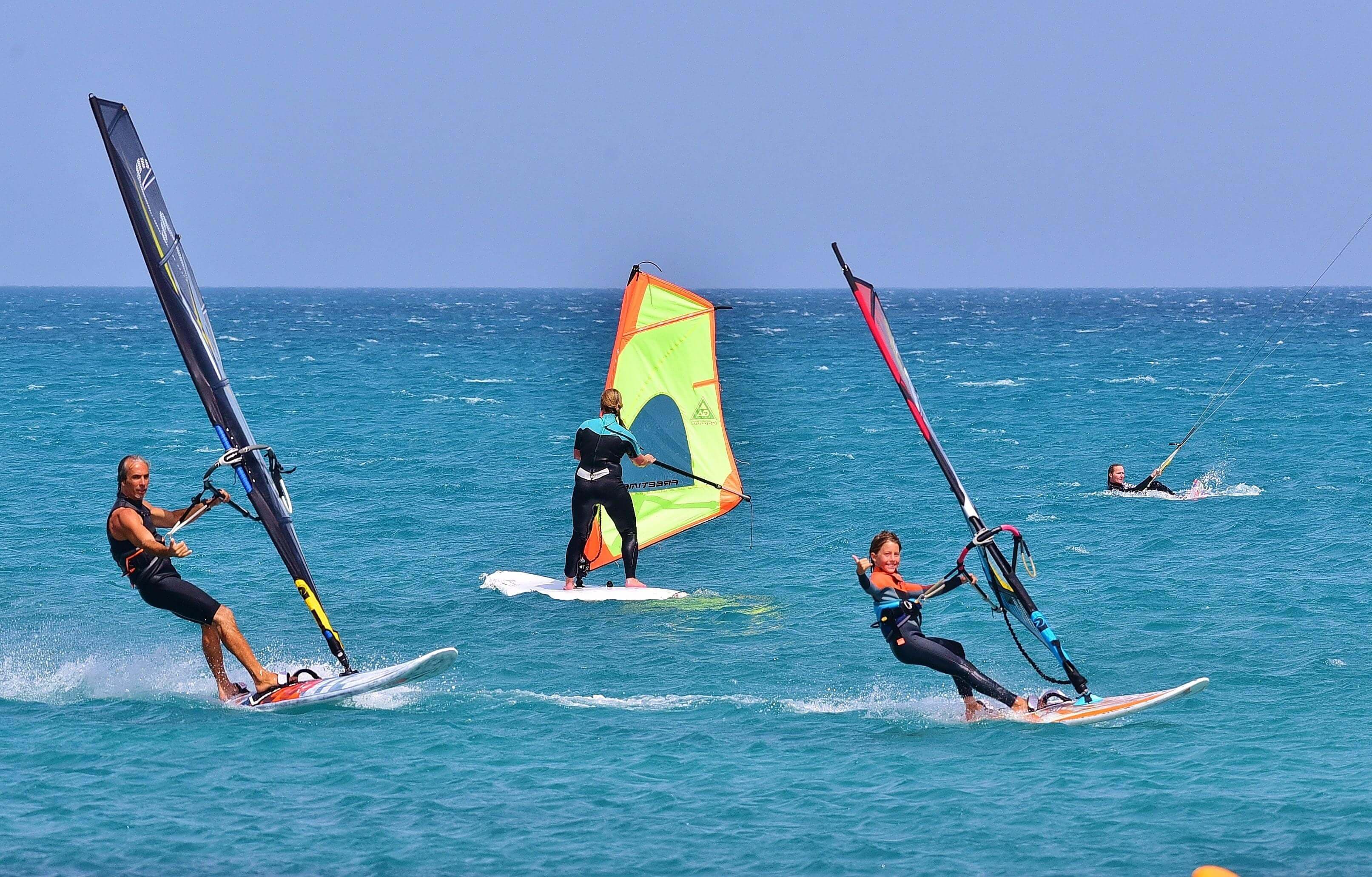 أربعة سائحين يمارسون رياضة ركوب الأمواج شراعيًا في بحر بينتوتا الجميل