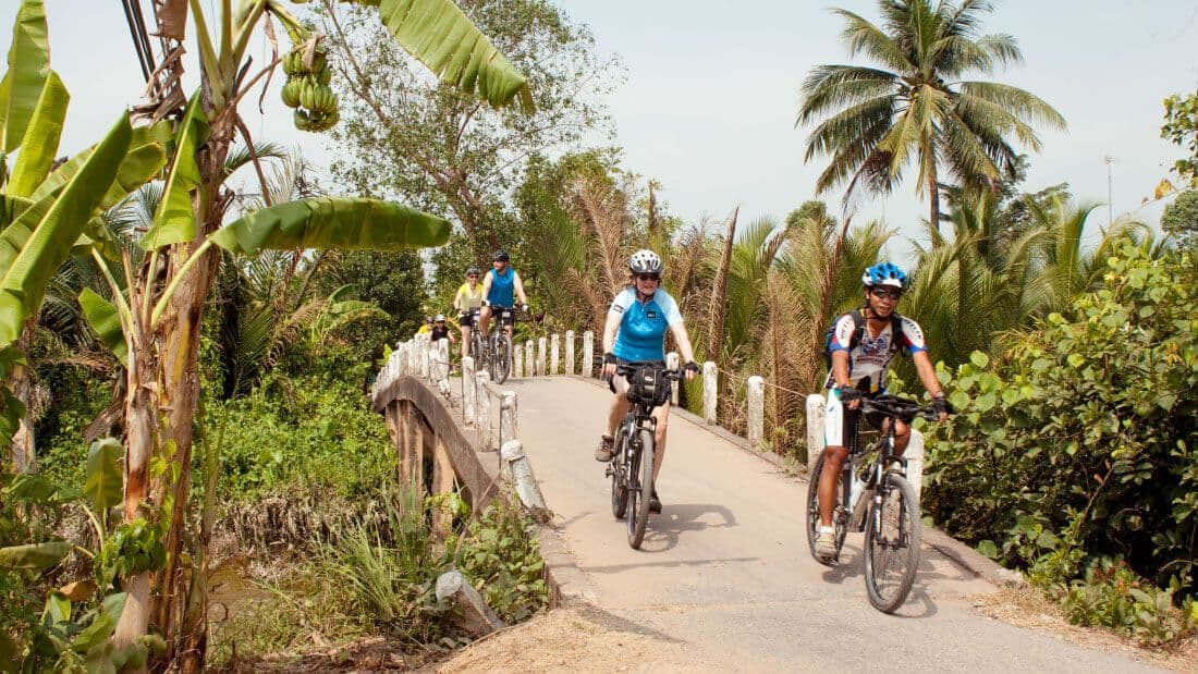 Группа велосипедистов пересекает мост во время тура по Негомбо, Шри-Ланка.