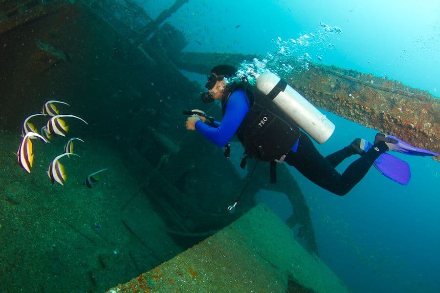 غواص يستكشف الأسماك بالقرب من حطام سفينة مغطاة بمرجان ناعم في كولومبو ، سريلانكا.