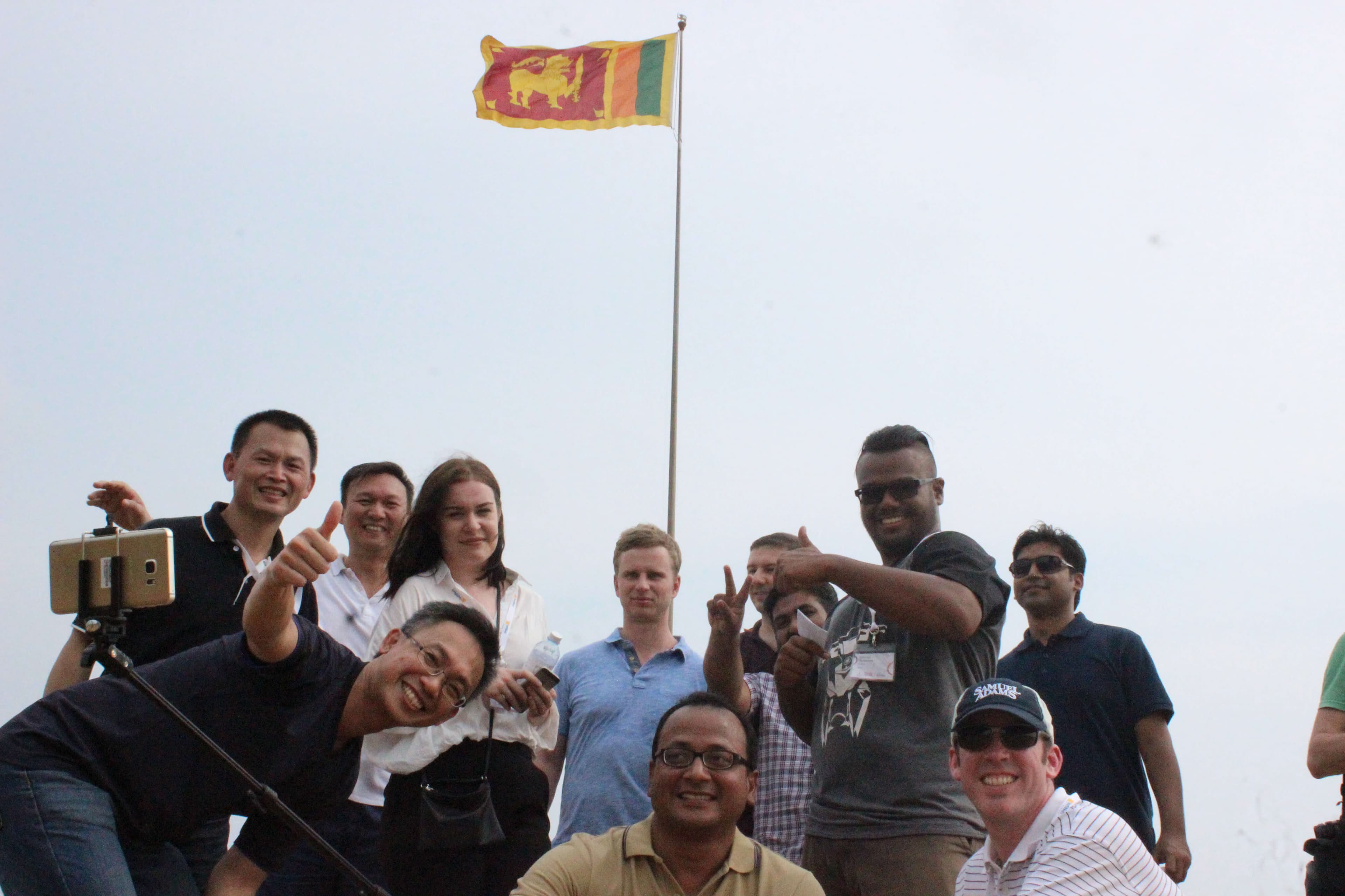 صورة جماعية للفريق مع العلم السريلانكي في الخلفية.
