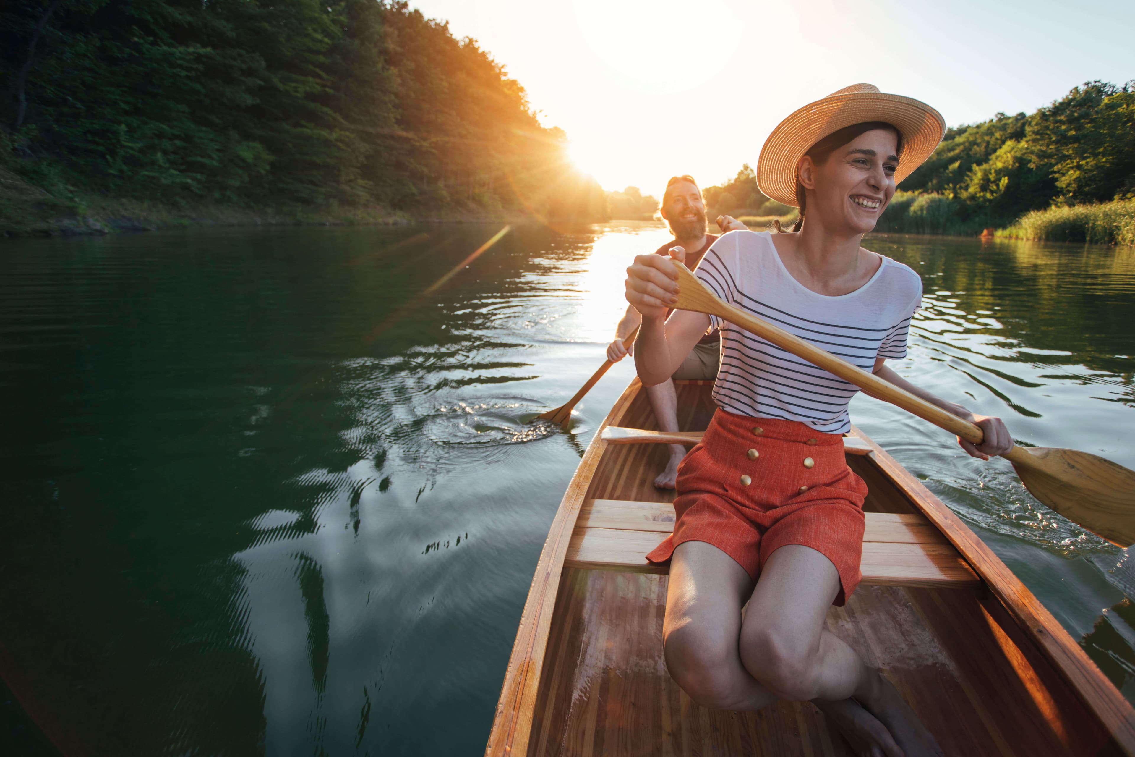Девушка и мужчина плывут на каноэ по реке Бентота с улыбающимися лицами.