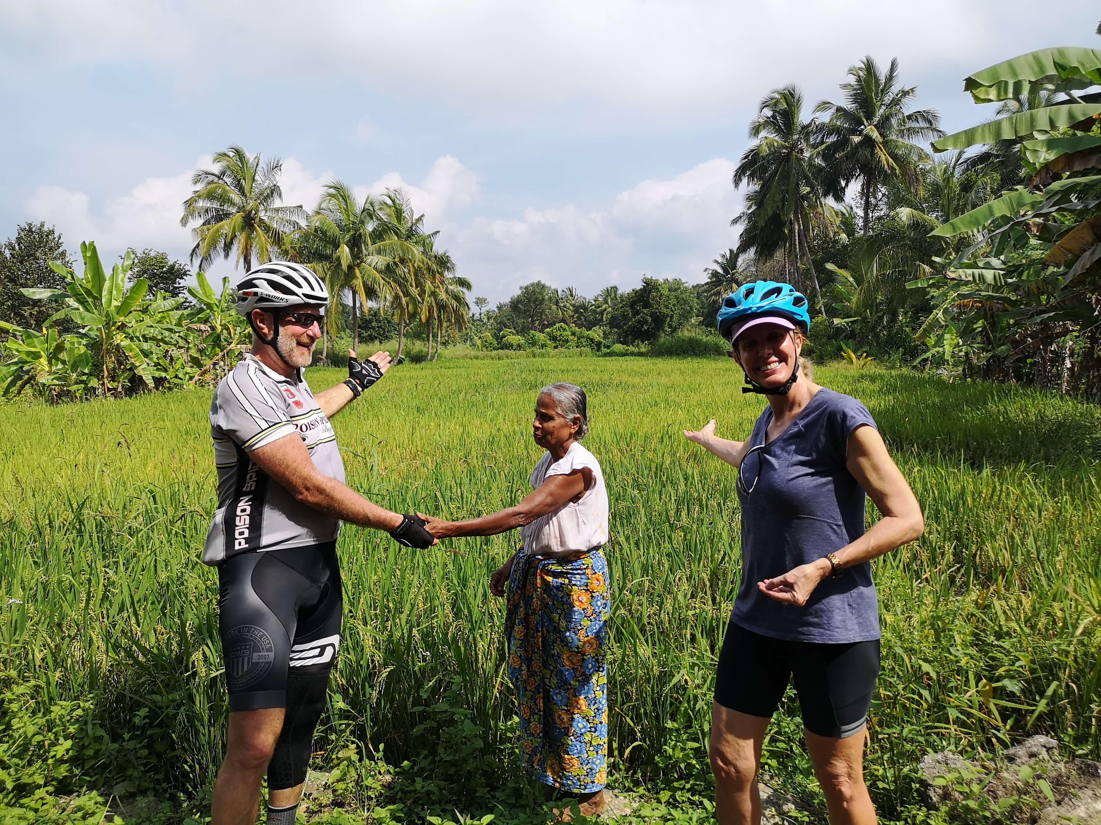 A photo of the cyclists watching a countryside paddy field with meeting local friendly people in Sri Lanka