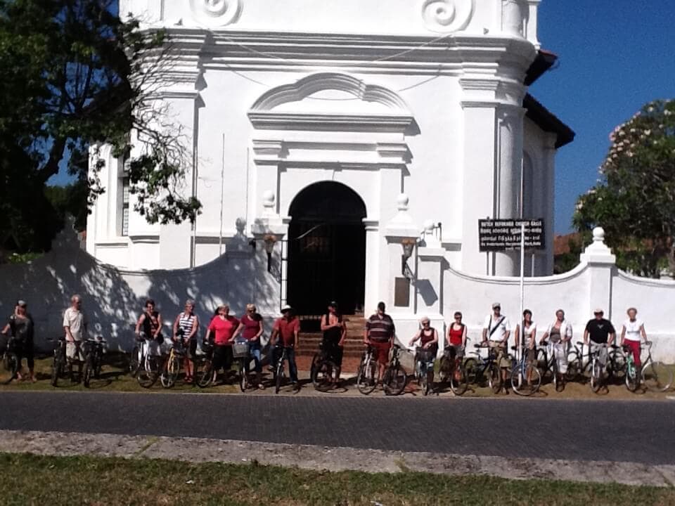 A picture of cyclists in front of Galle fort Duch Reformed Church in Sri Lanka