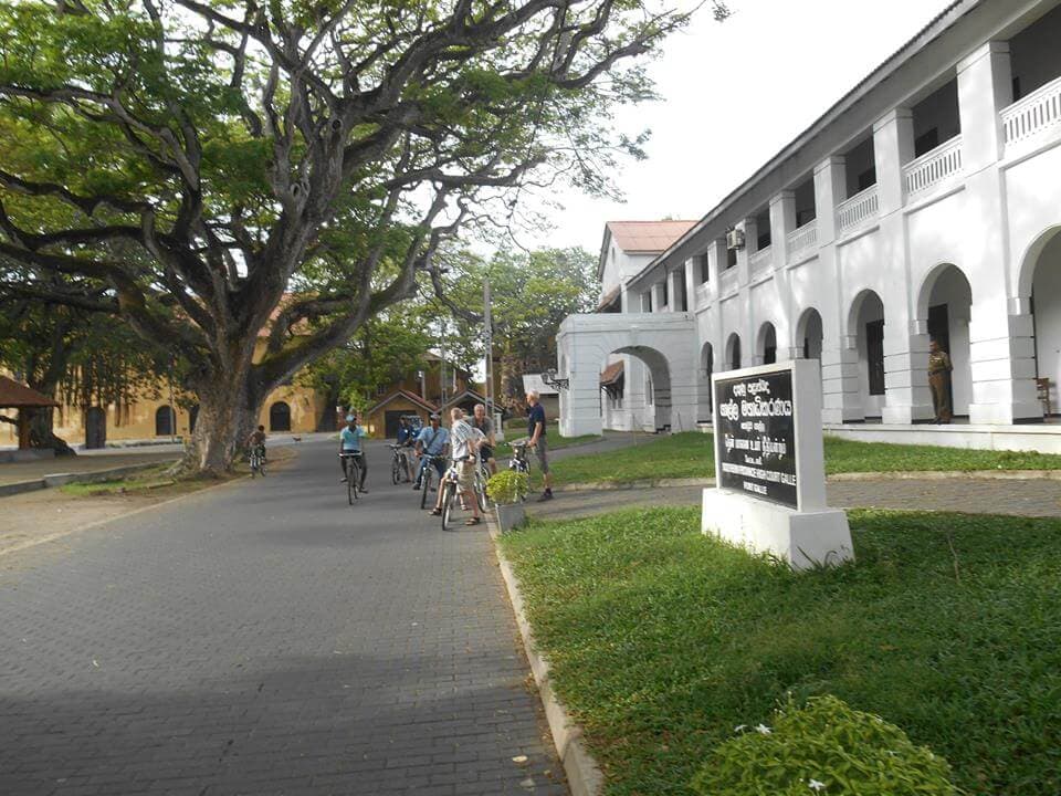 A photo of cyclists watching District court Galle fort in Sri Lanka