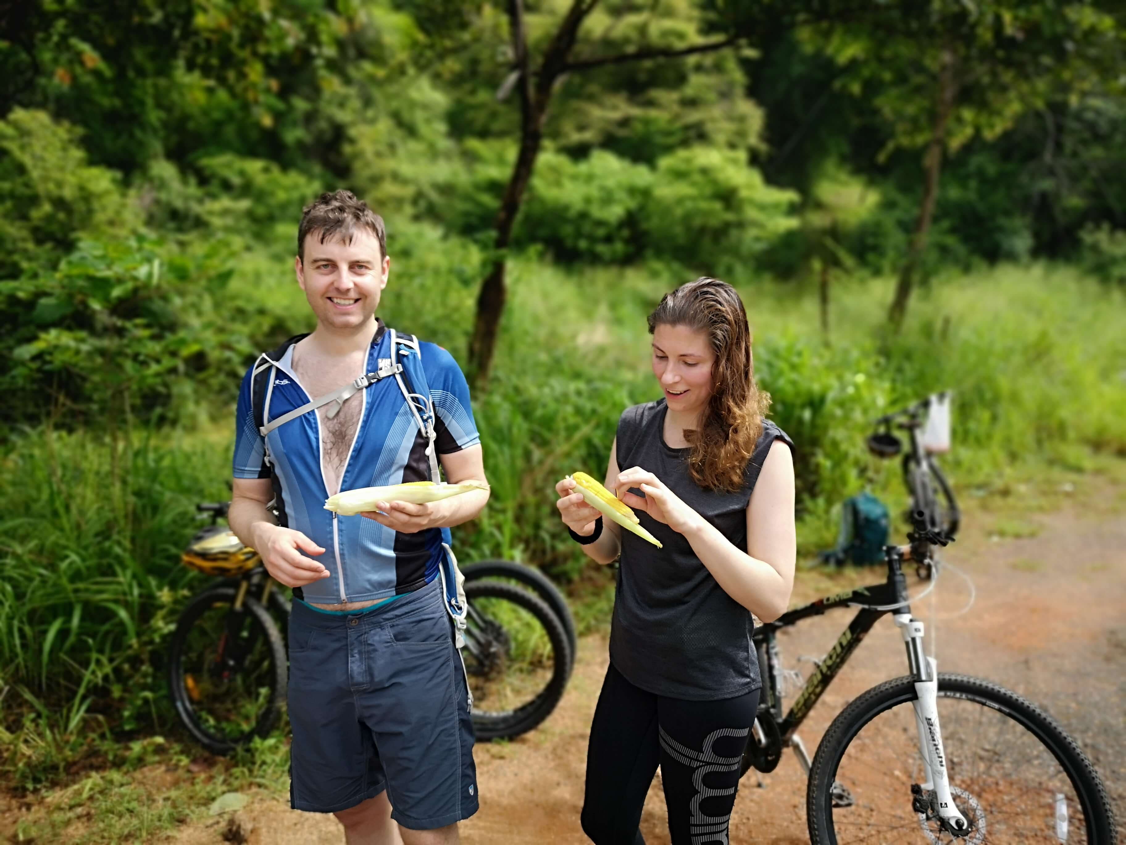 Ein radfahrendes Paar, das während des Radfahrens in der Landschaft von Galle Sri Lanka mit heißen Maissamen isst