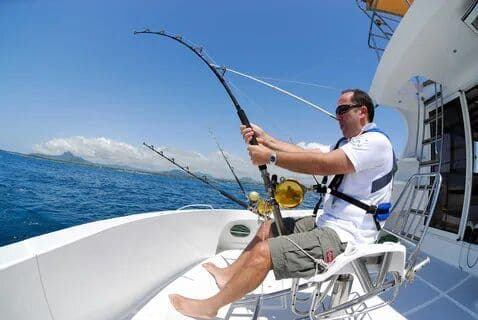 A man fishing freely sitting on the boat top