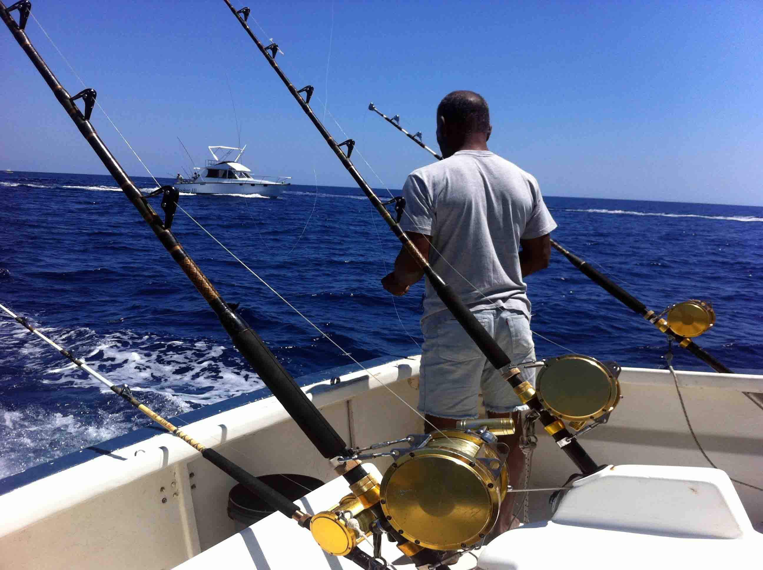 رجل يرتدي معدات صيد على رأس قارب الصيد