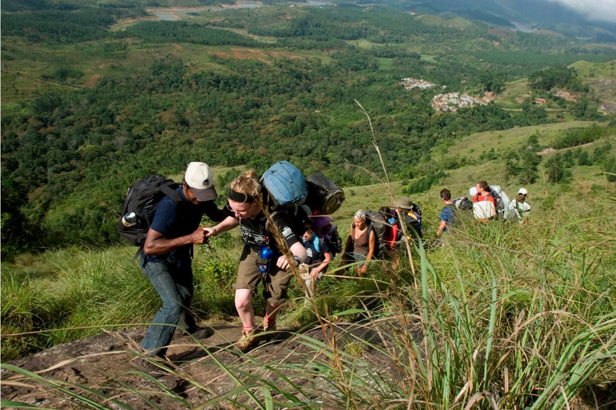 The tourists hiking Knuckles mountain with the help of guide in Sri Lanka