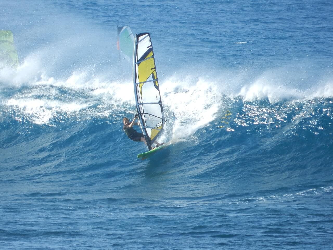 A scene of a young woman windsurfing on rough wave