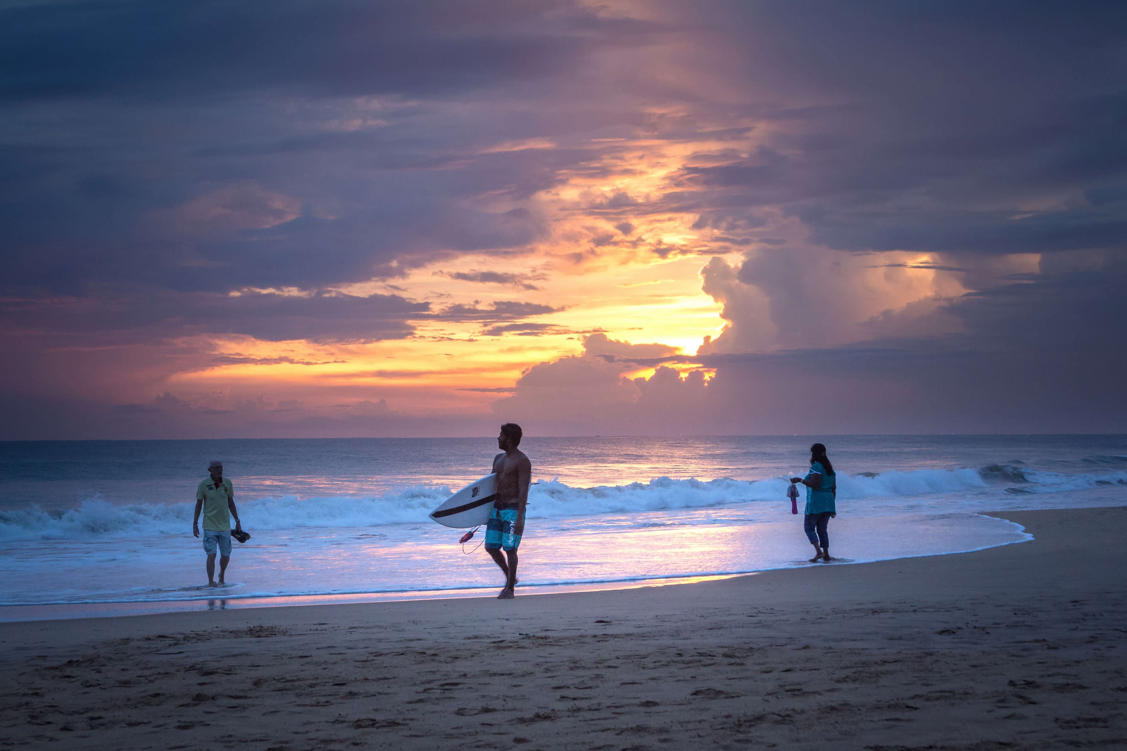أشخاص يمشون على شاطئ هيكادوا عند غروب الشمس في هيكادوا ، سريلانكا.