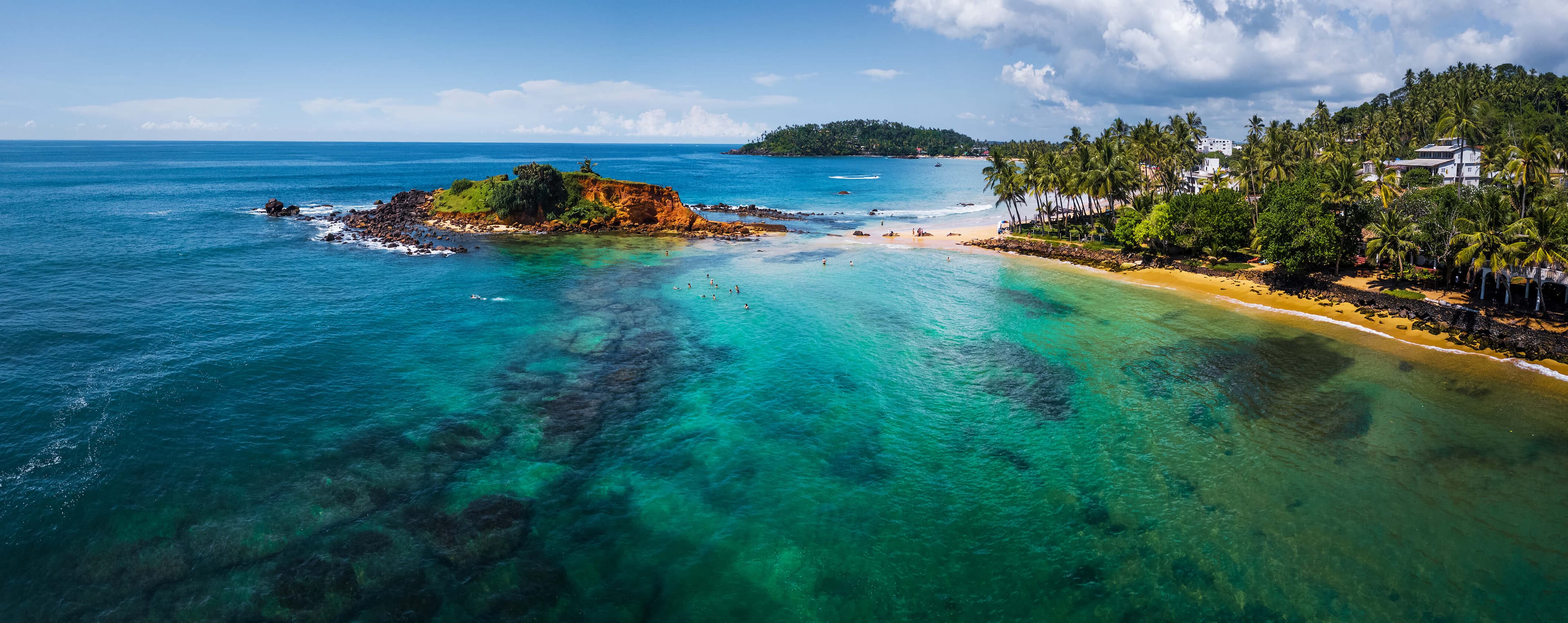 Aerial panorama of the tropical beach and clear sea with coral reefs in the town of Mirissa, Sri Lanka.